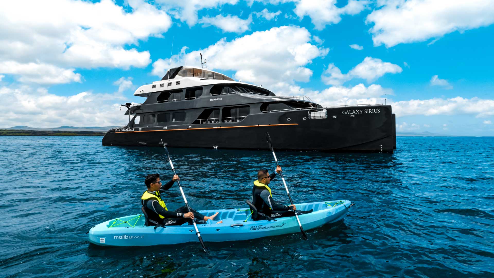 Travelers kayaking beside the Sirius yacht in the Galapagos
